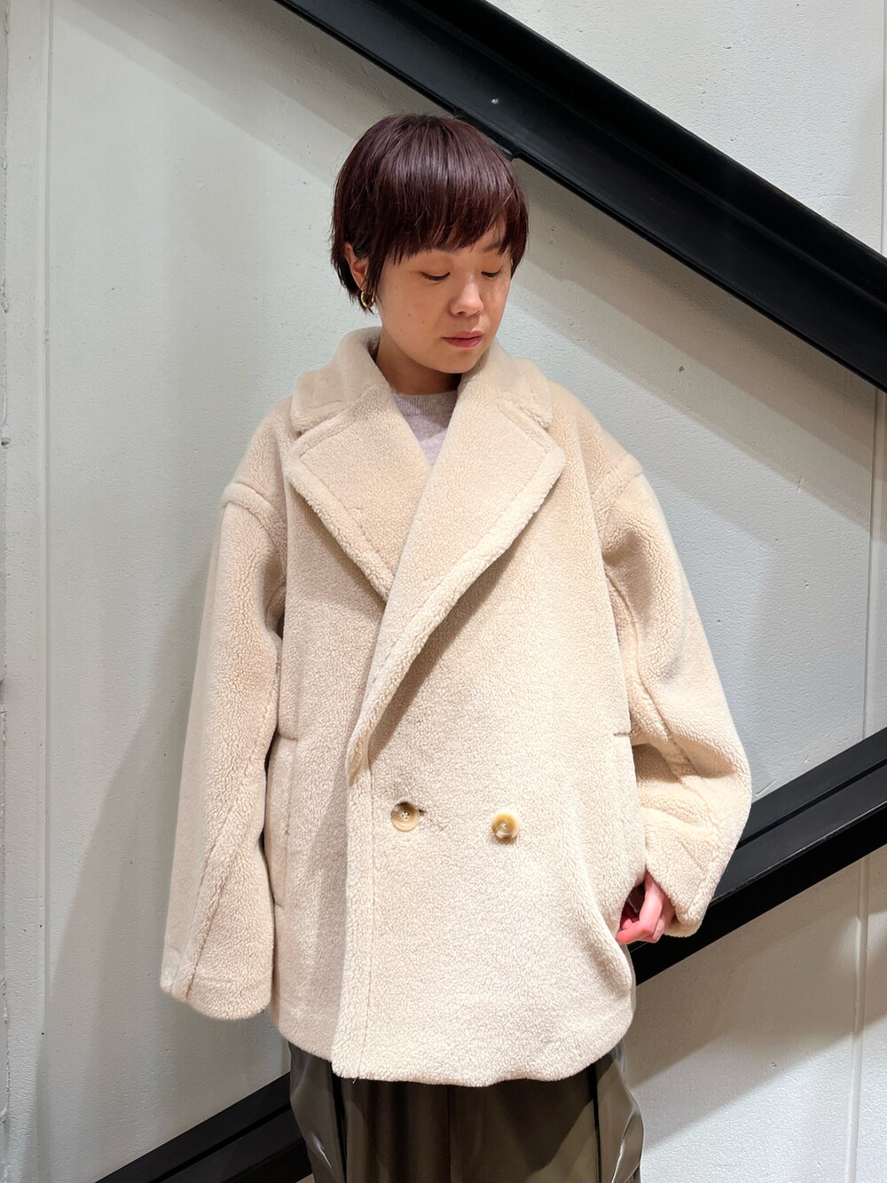 ブラック系のハンドバッグ、ホワイト系のピーコート、ベージュ系のニット/セーターを着用したレディースの冬コーディネートの4枚目の写真