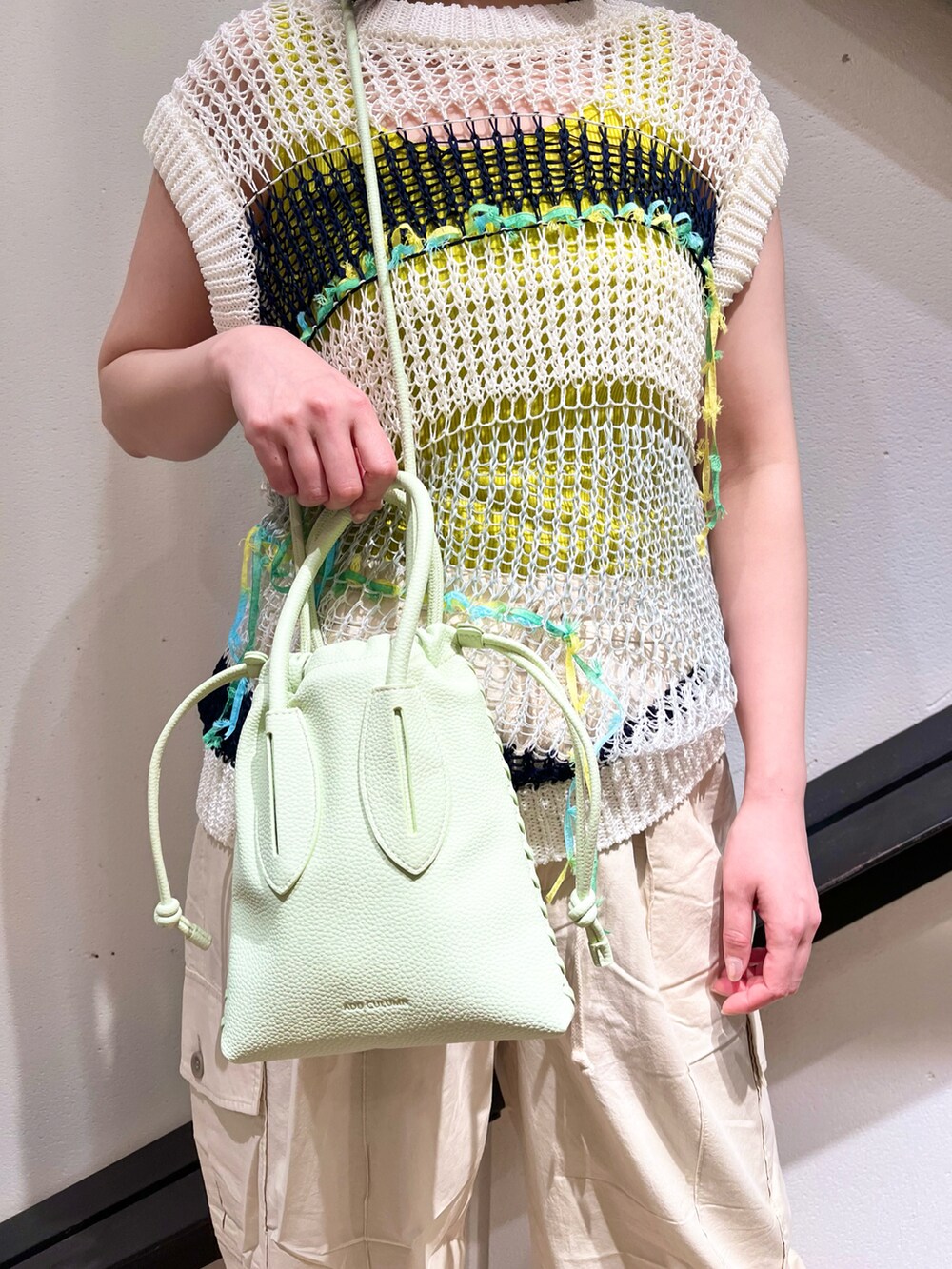 ホワイト系のニット/セーター、グリーン系のショルダーバッグ、ホワイト系のカーゴパンツを着用したレディースの夏コーディネートの3枚目の写真