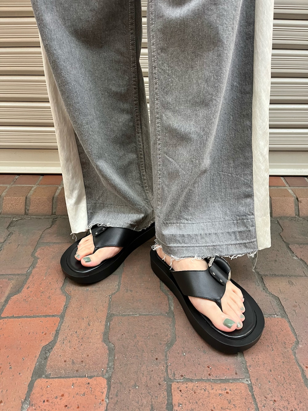 ブラック系のサンダル、グレー系のデニムパンツ、ブラック系のTシャツ/カットソーを着用したレディースの春コーディネートの4枚目の写真