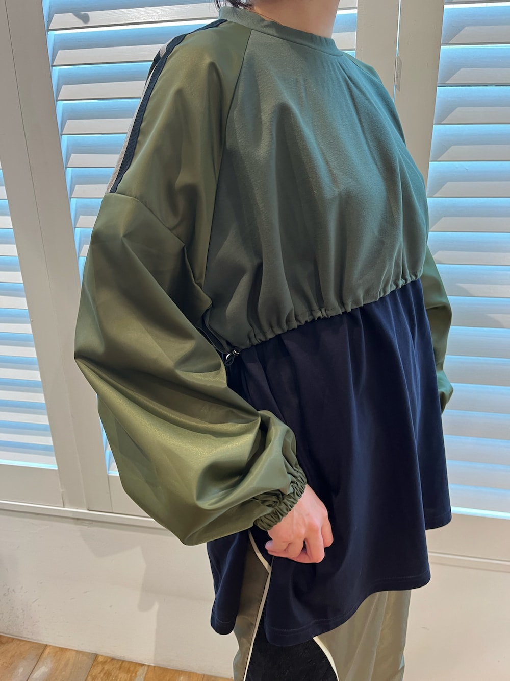 グリーン系のTシャツ/カットソー、グリーン系のスカート、ブラック系のスニーカーを着用したレディースの秋コーディネートの2枚目の写真