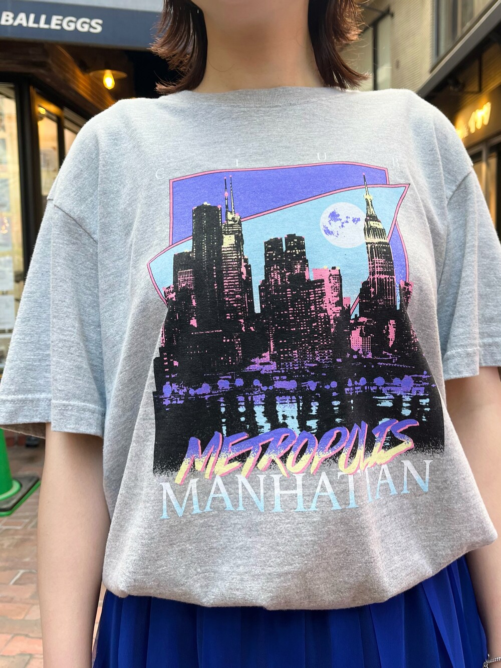 グレー系のTシャツ/カットソー、ブラック系のハンドバッグ、ブルー系のスカートを着用したレディースの秋コーディネートの2枚目の写真