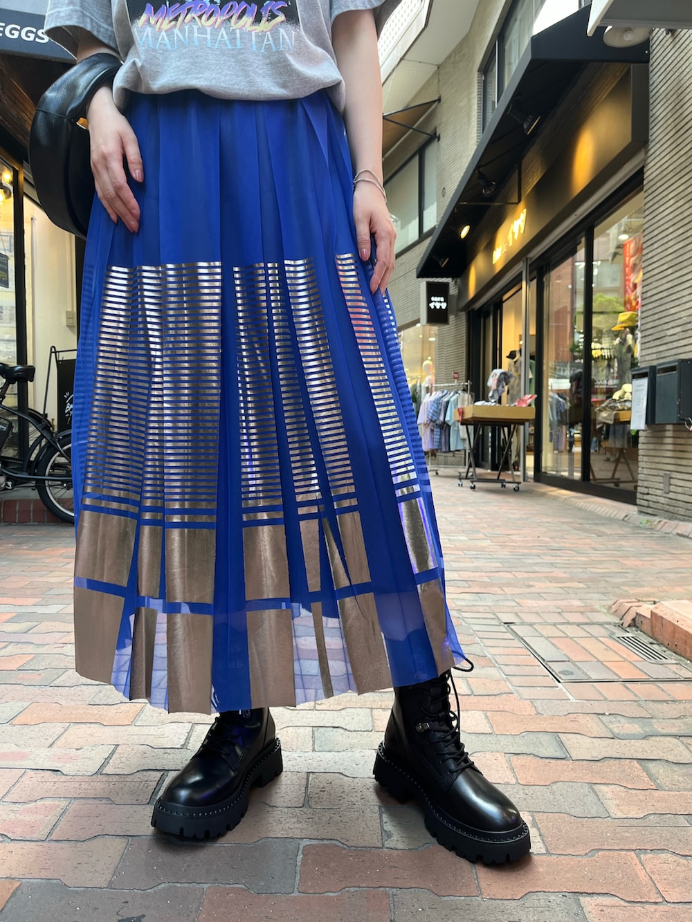 グレー系のTシャツ/カットソー、ブラック系のハンドバッグ、ブルー系のスカートを着用したレディースの秋コーディネートの4枚目の写真