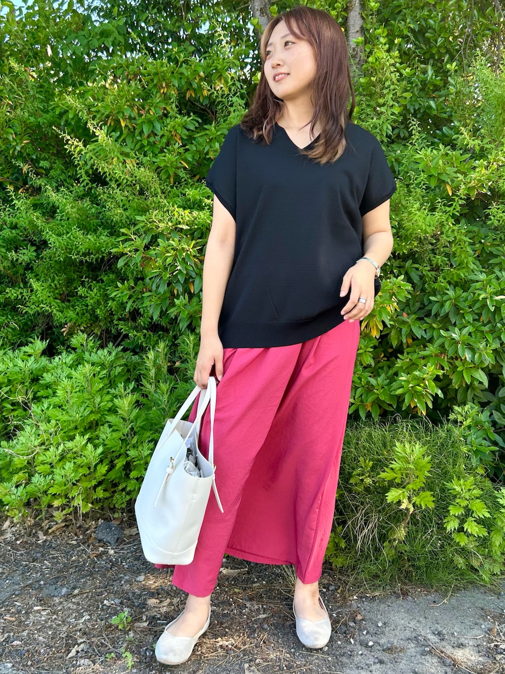 ブラック系のニット/セーター、ホワイト系のトートバッグ、レッド系のスカートを着用したレディースの夏コーディネートの2枚目の写真