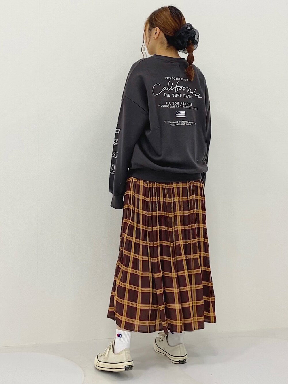 グレー系のスウェット、ブラウン系のスカート、ゴールド系のピアス（両耳用）を着用したレディースの秋コーディネートの2枚目の写真