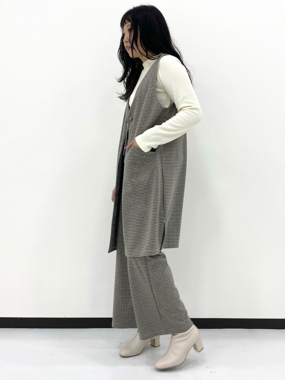 ホワイト系のトップス、グレー系のパンツ、グレー系のトップスを着用したレディースの冬コーディネートの2枚目の写真