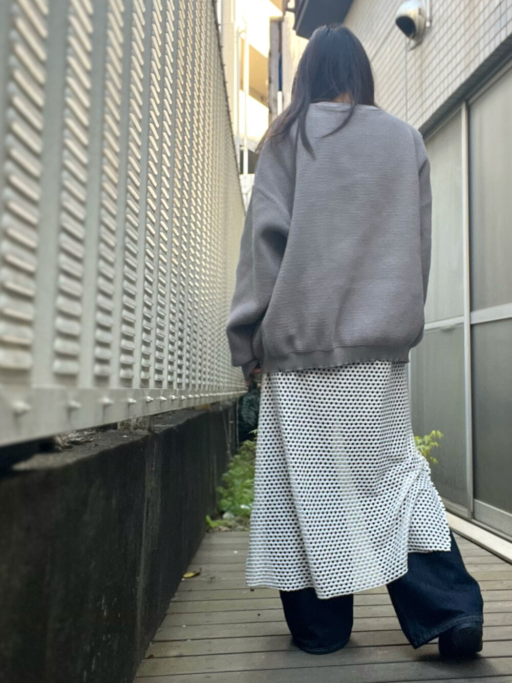 ホワイト系のワンピース、グレー系のニット/セーター、ブルー系のデニムパンツを着用したレディースの春コーディネートの2枚目の写真