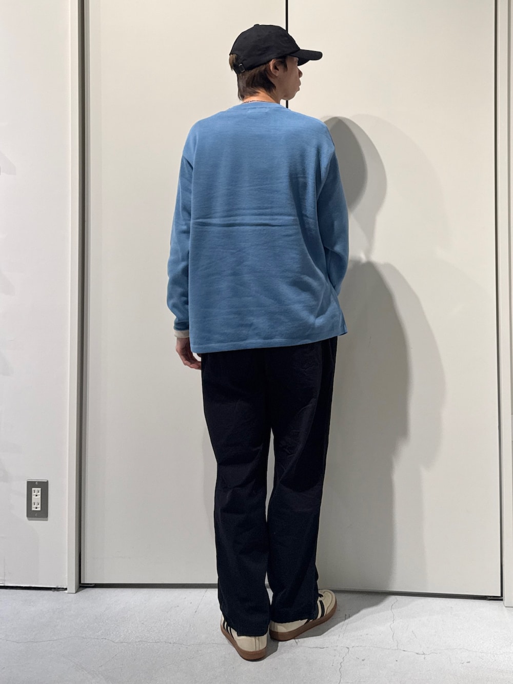 ブルー系のニット/セーター、ブラック系のカーゴパンツ、ブラック系のキャップを着用したメンズの春コーディネートの2枚目の写真