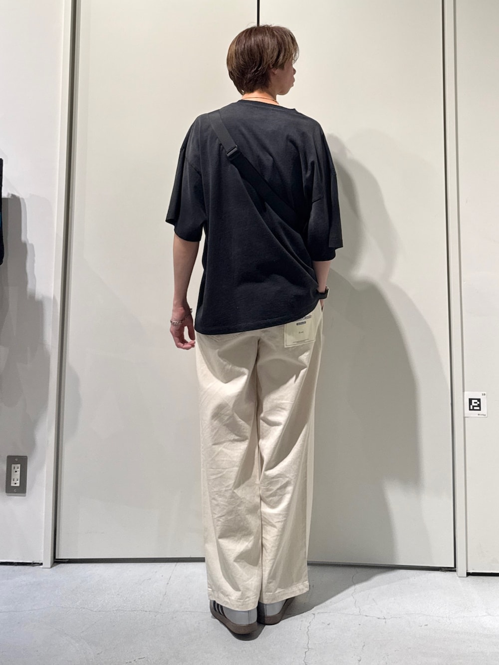 ブラック系のTシャツ/カットソー、シルバー系のボディバッグ/ウエストポーチ、ホワイト系のデニムパンツを着用したメンズの春コーディネートの2枚目の写真