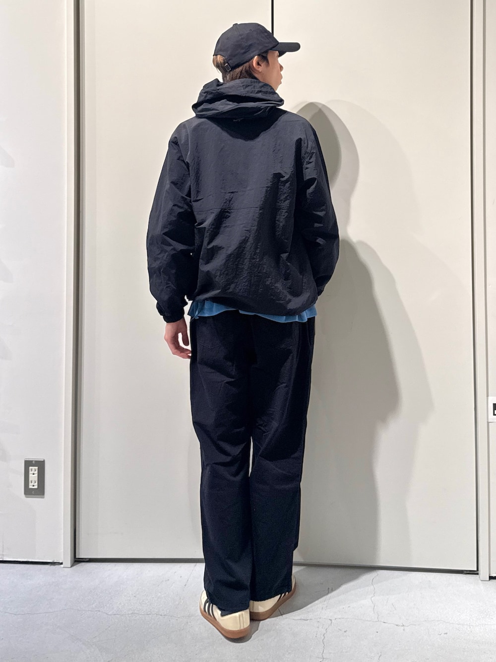 ブラック系のマウンテンパーカー、ブルー系のニット/セーター、ブラック系のカーゴパンツを着用したメンズの春コーディネートの2枚目の写真