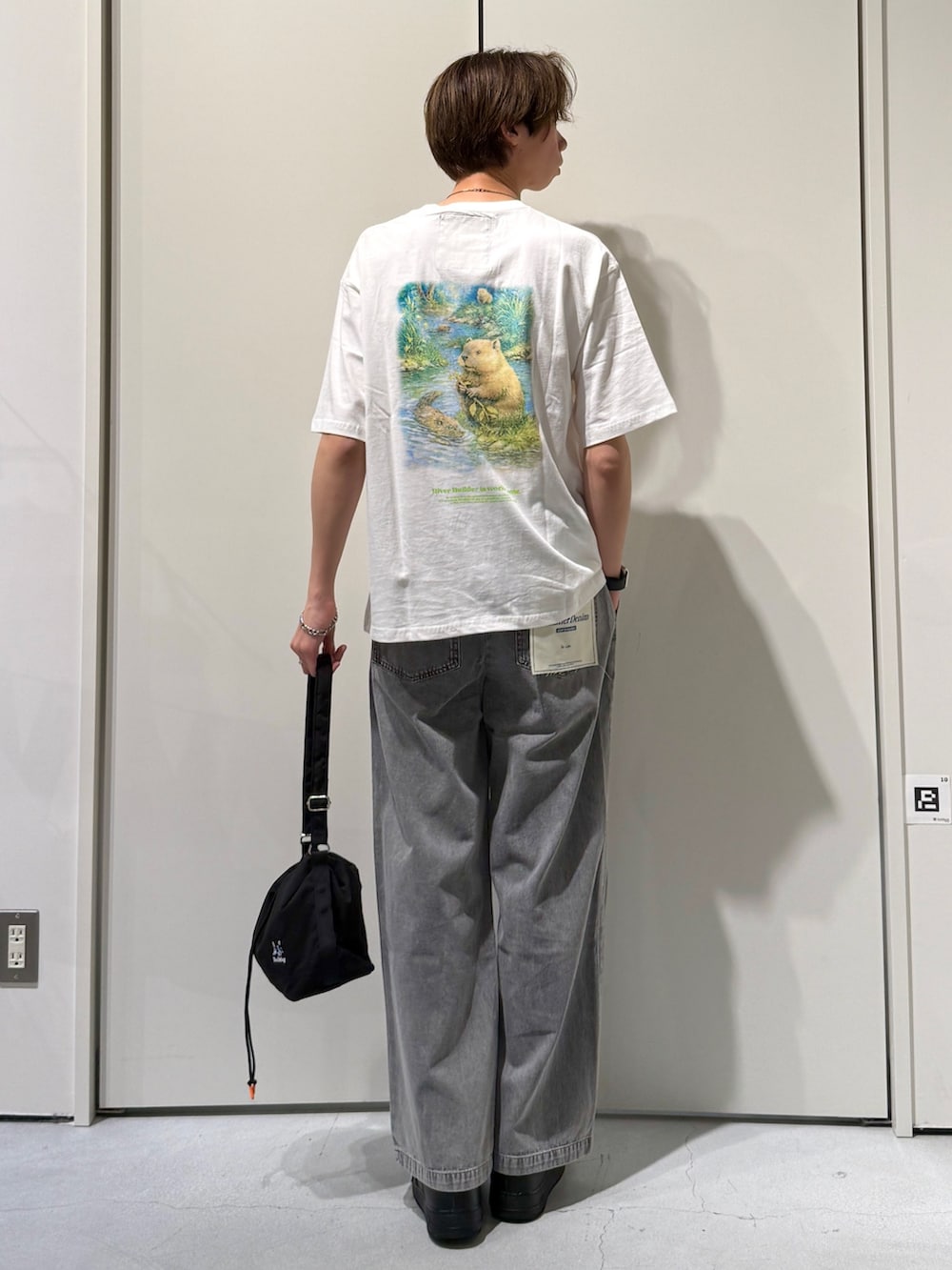 ホワイト系のTシャツ/カットソー、ブラック系のショルダーバッグ、グレー系のデニムパンツを着用したメンズの春コーディネートの2枚目の写真