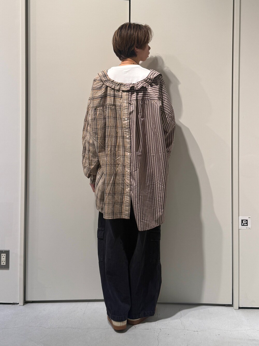 ブラウン系のスカート、ブラック系のカーゴパンツを着用したメンズの春コーディネートの2枚目の写真