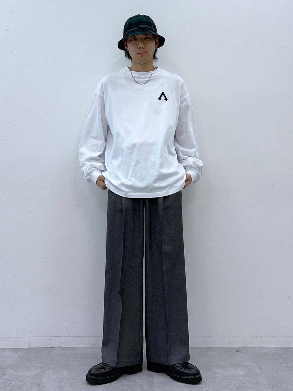 グレー系のスラックス、ブラック系のドレスシューズ、ホワイト系のTシャツ/カットソーを着用したメンズの冬コーディネートの2枚目の写真