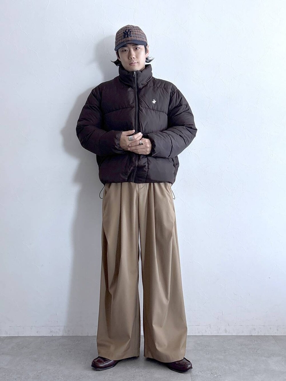 ブラウン系のダウンジャケット/コート、ベージュ系のスラックス、ブラウン系のキャップを着用したメンズの冬コーディネートの2枚目の写真