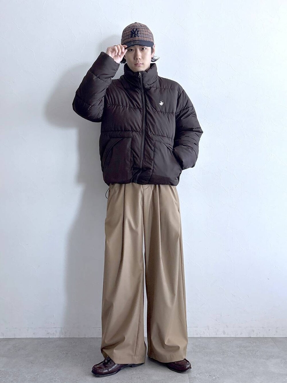 ブラウン系のダウンジャケット/コート、ベージュ系のスラックス、ブラウン系のキャップを着用したメンズの冬コーディネートの3枚目の写真