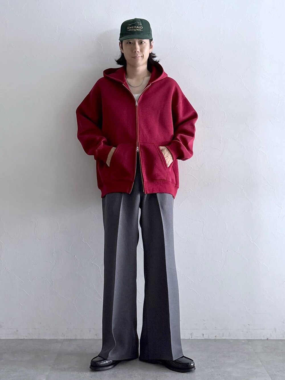 グレー系のスラックス、レッド系のパーカー、その他のネックレスを着用したメンズの秋コーディネートの4枚目の写真