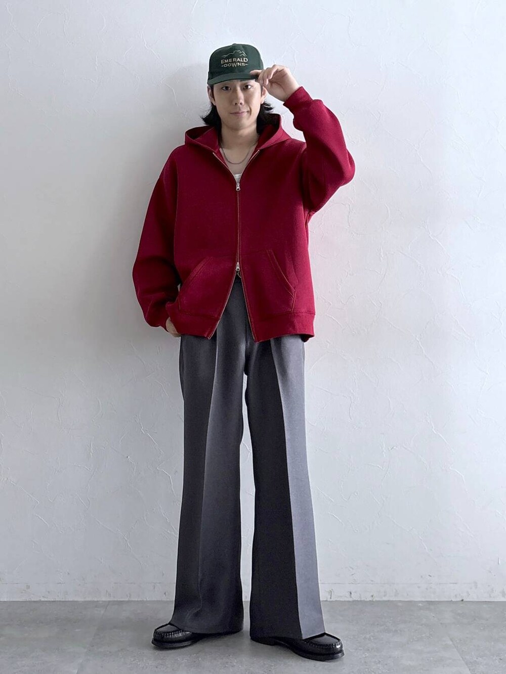 グレー系のスラックス、レッド系のパーカー、その他のネックレスを着用したメンズの秋コーディネートの3枚目の写真