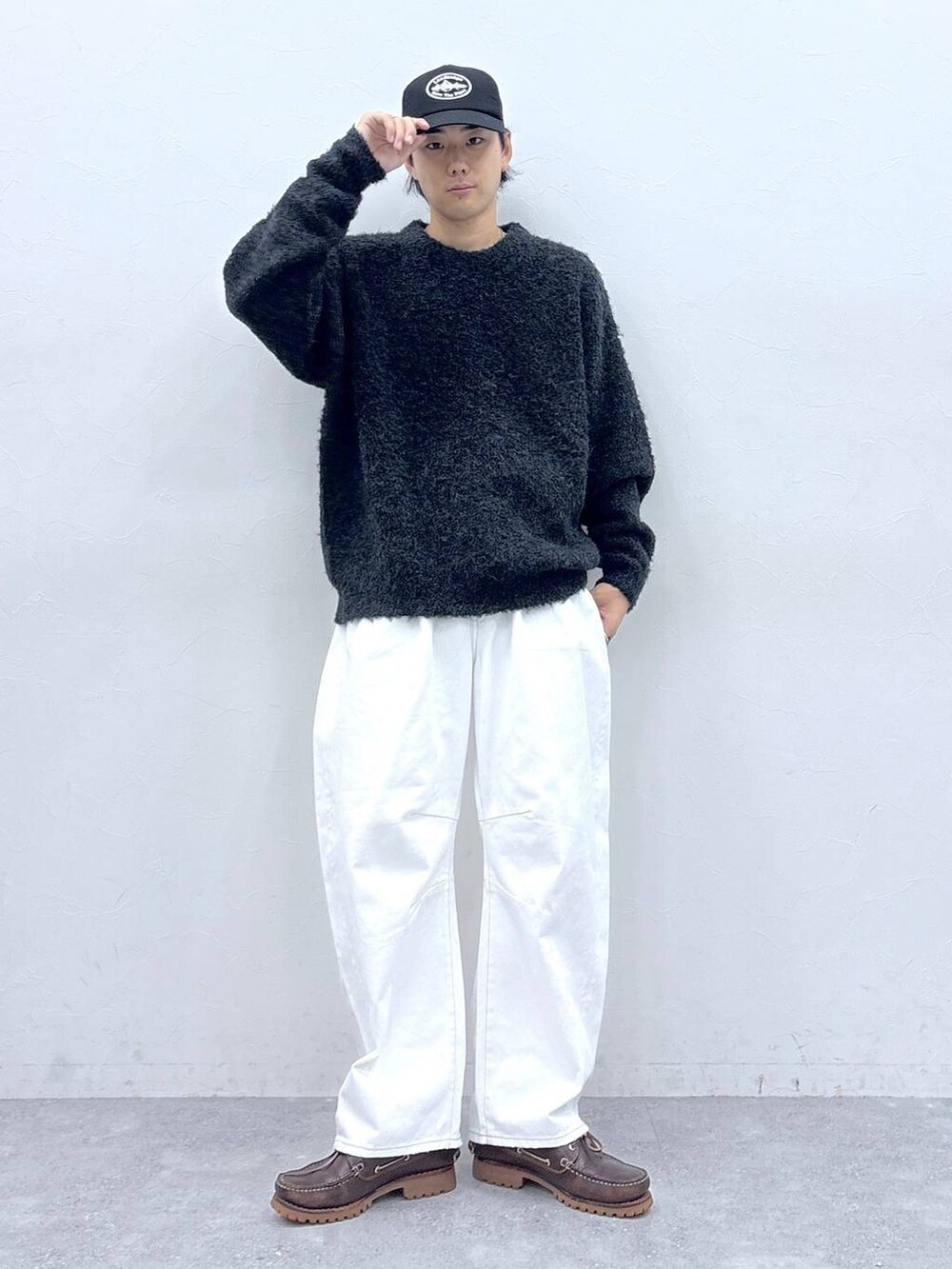 グレー系のニット/セーター、ホワイト系のデニムパンツ、ブラック系のキャップを着用したメンズの秋コーディネートの3枚目の写真