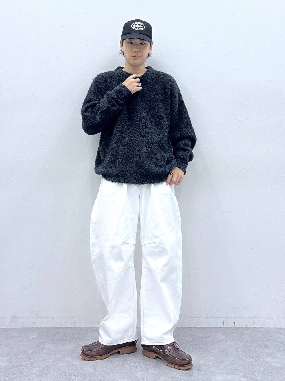 グレー系のニット/セーター、ホワイト系のデニムパンツ、ブラック系のキャップを着用したメンズの秋コーディネートの4枚目の写真