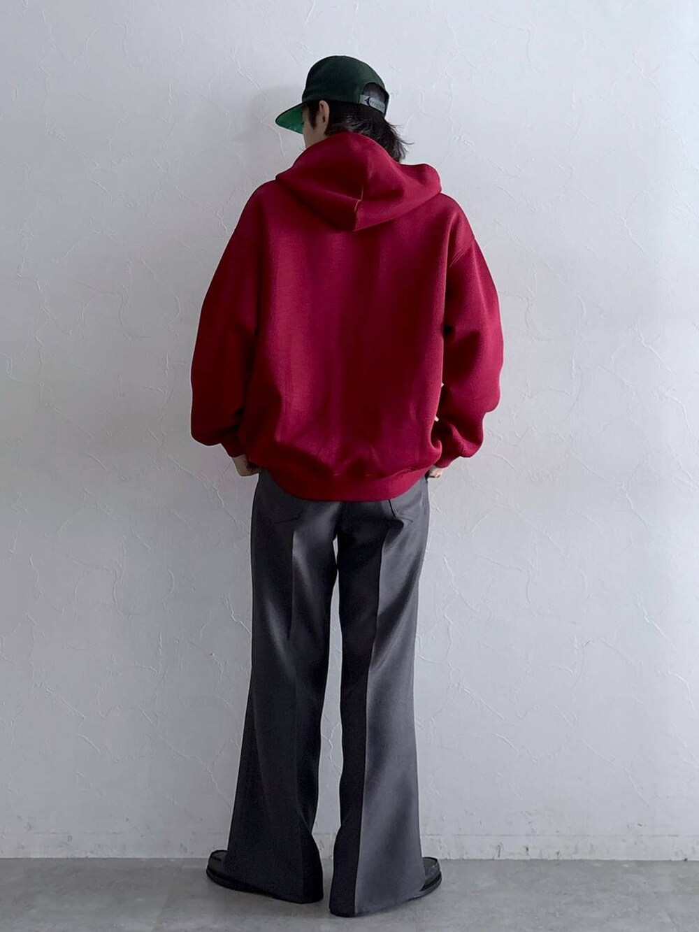 グレー系のスラックス、レッド系のパーカー、その他のネックレスを着用したメンズの秋コーディネートの6枚目の写真