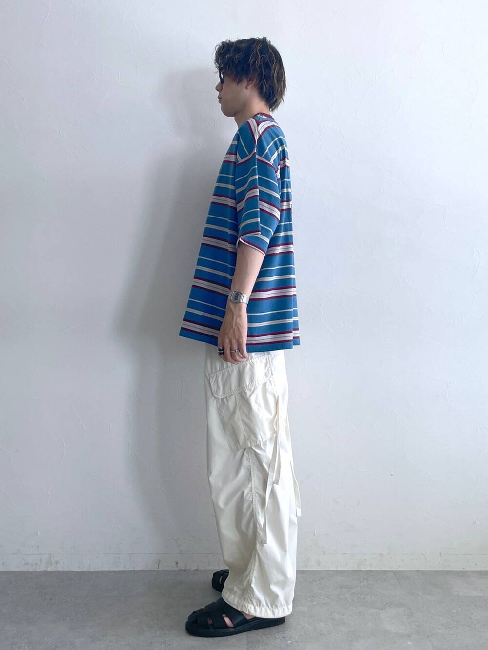 ブラック系のサンダル、ブルー系のTシャツ/カットソー、ホワイト系のカーゴパンツを着用したメンズの夏コーディネートの4枚目の写真