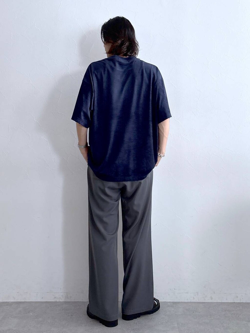 グレー系のスラックス、ブラック系のサンダル、ブルー系のTシャツ/カットソーを着用したメンズの夏コーディネートの4枚目の写真