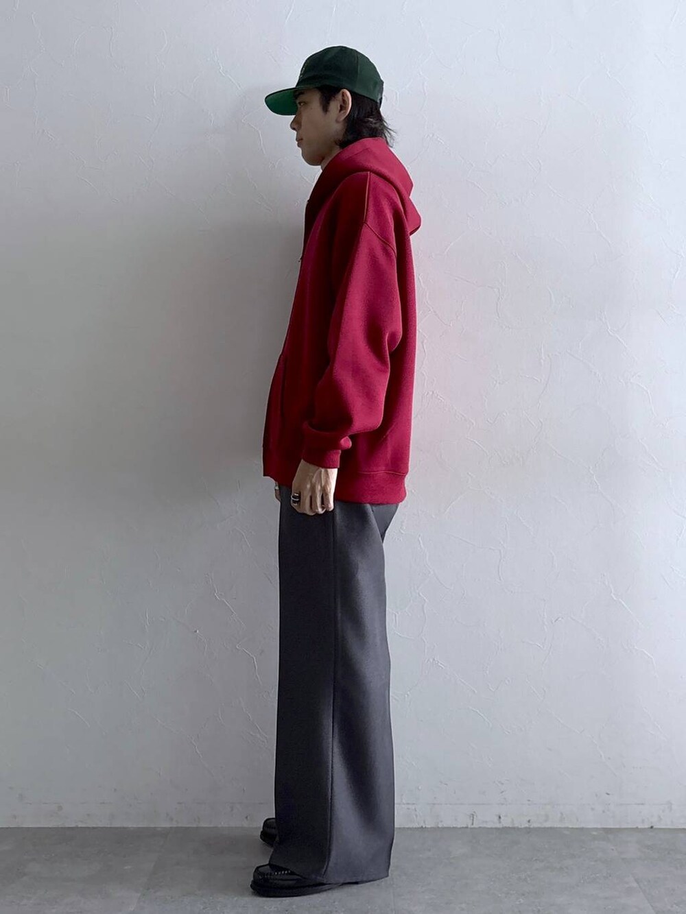 グレー系のスラックス、レッド系のパーカー、その他のネックレスを着用したメンズの秋コーディネートの5枚目の写真