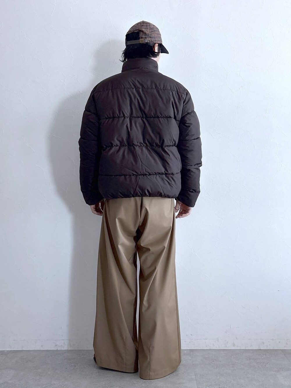 ブラウン系のダウンジャケット/コート、ベージュ系のスラックス、ブラウン系のキャップを着用したメンズの冬コーディネートの5枚目の写真