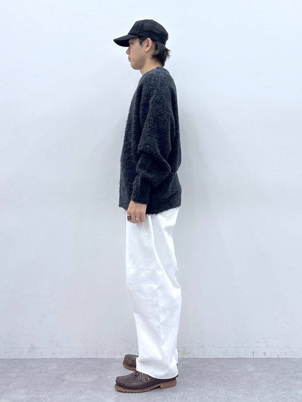 グレー系のニット/セーター、ホワイト系のデニムパンツ、ブラック系のキャップを着用したメンズの秋コーディネートの5枚目の写真