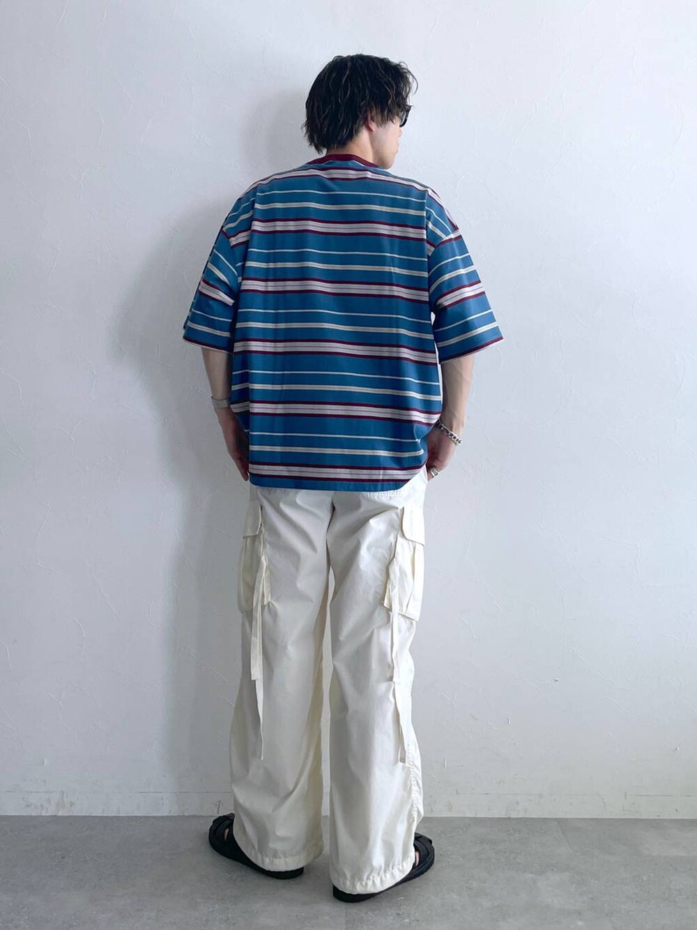 ブラック系のサンダル、ブルー系のTシャツ/カットソー、ホワイト系のカーゴパンツを着用したメンズの夏コーディネートの5枚目の写真