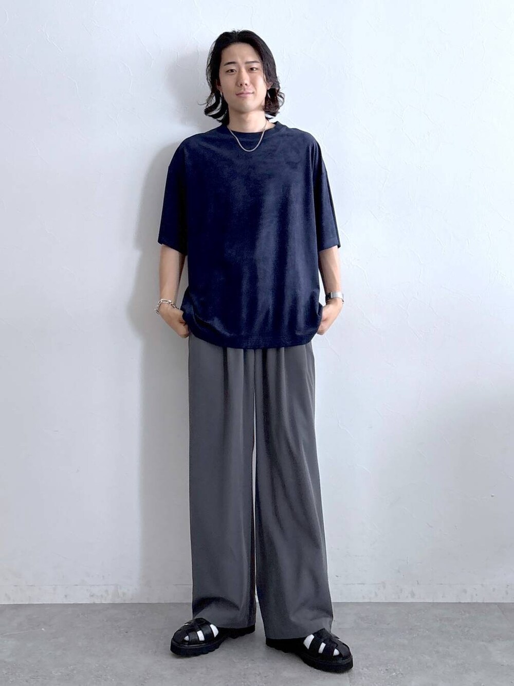 グレー系のスラックス、ブラック系のサンダル、ブルー系のTシャツ/カットソーを着用したメンズの夏コーディネートの2枚目の写真