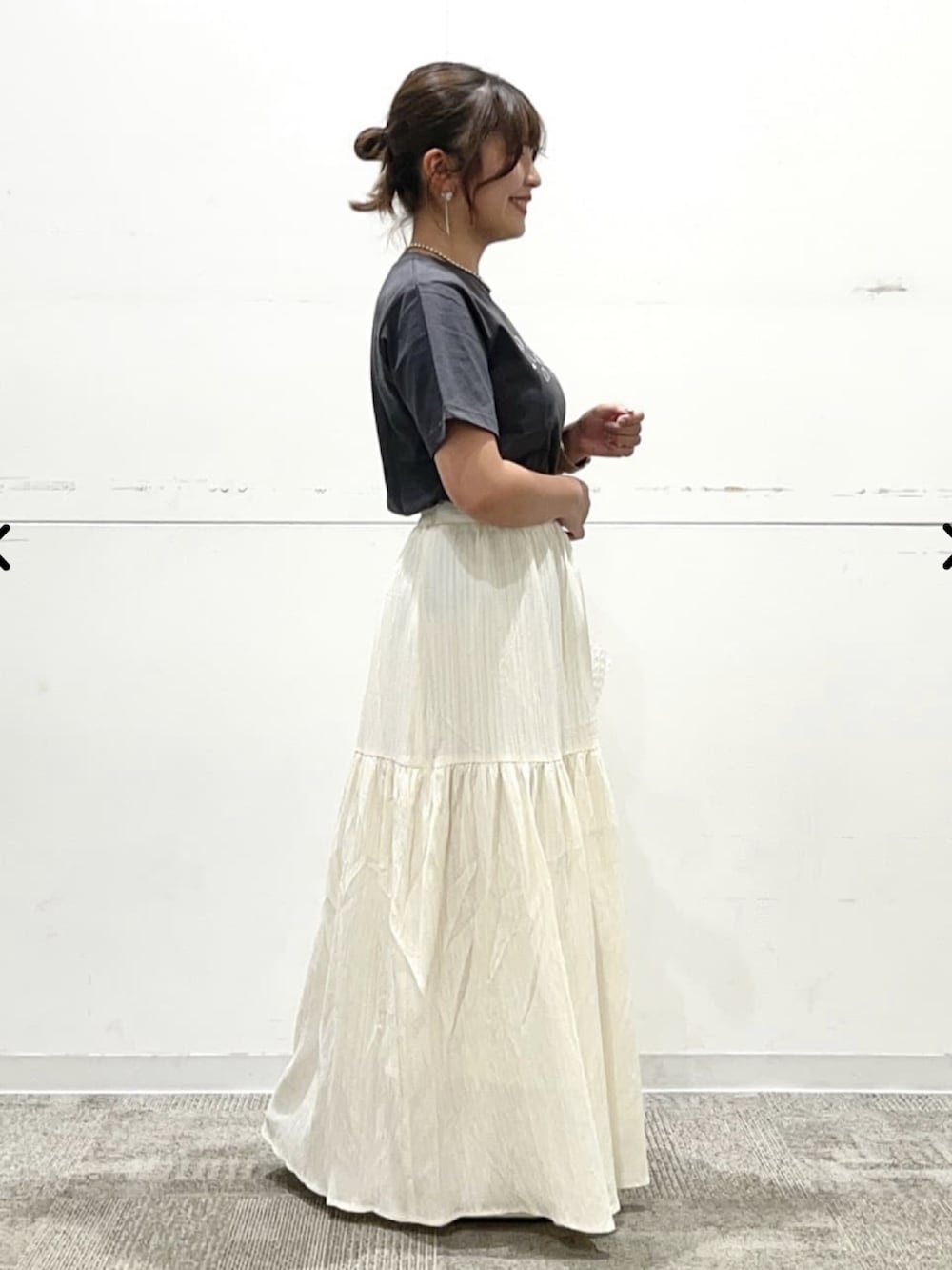 グレー系のTシャツ/カットソー、ホワイト系のスカート、シルバー系のネックレスを着用したレディースの夏コーディネートの2枚目の写真