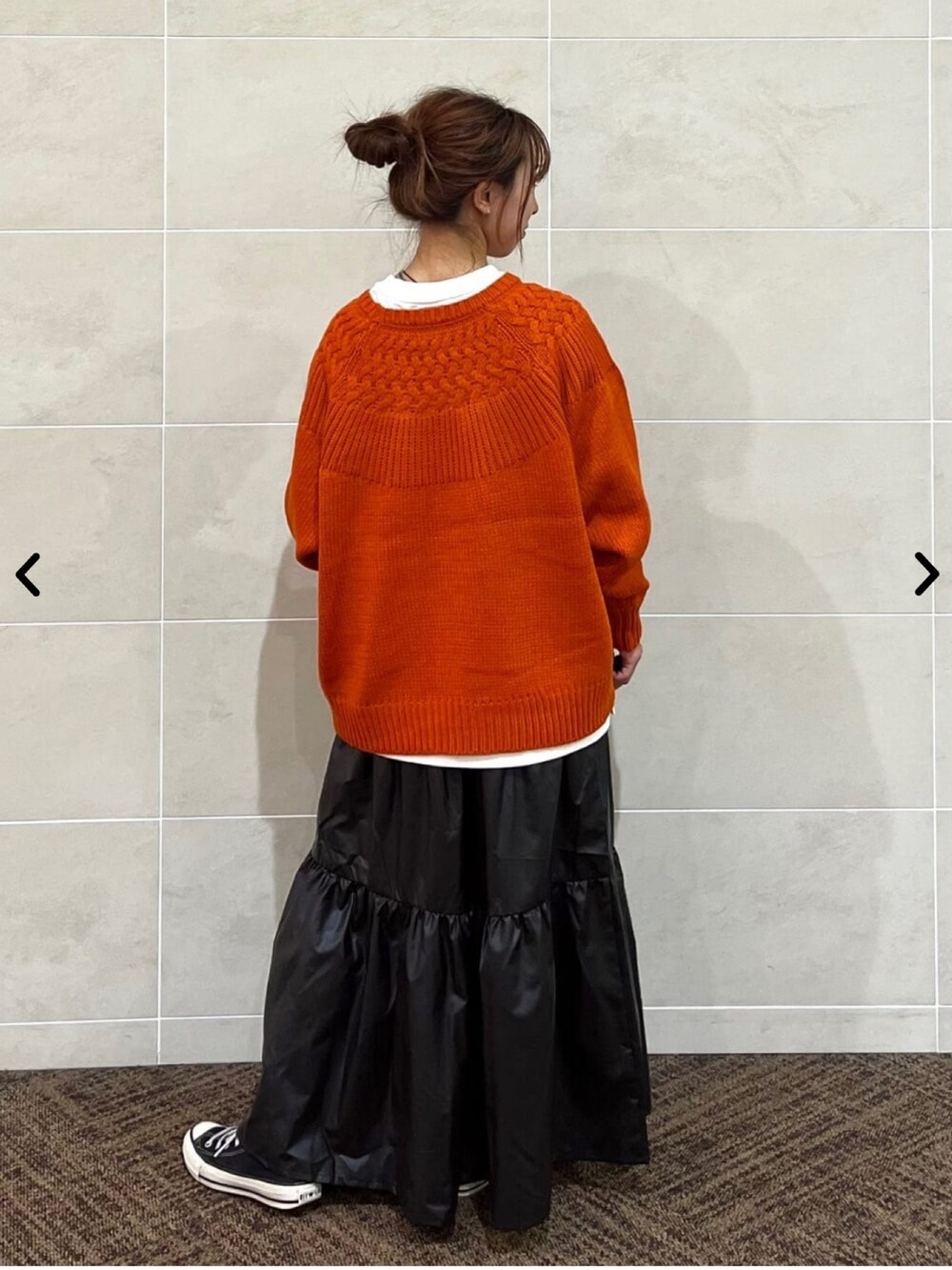 オレンジ系のニット/セーター、ブラック系のスカートを着用したレディースの秋コーディネートの3枚目の写真
