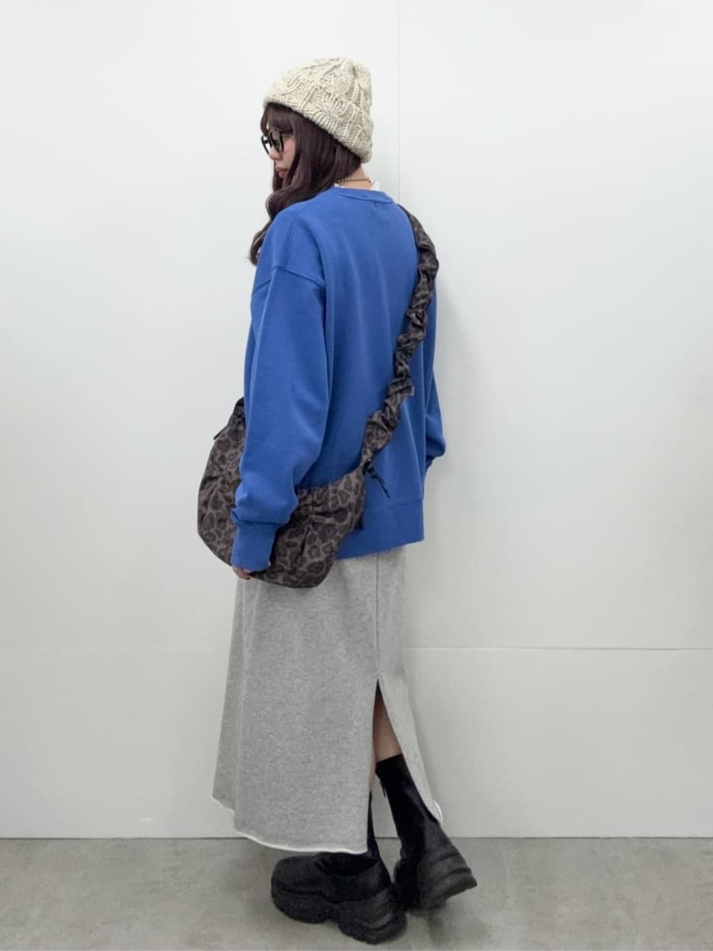 グレー系のスカート、ブラック系のブーツ、ホワイト系のTシャツ/カットソーを着用したレディースの冬コーディネートの2枚目の写真