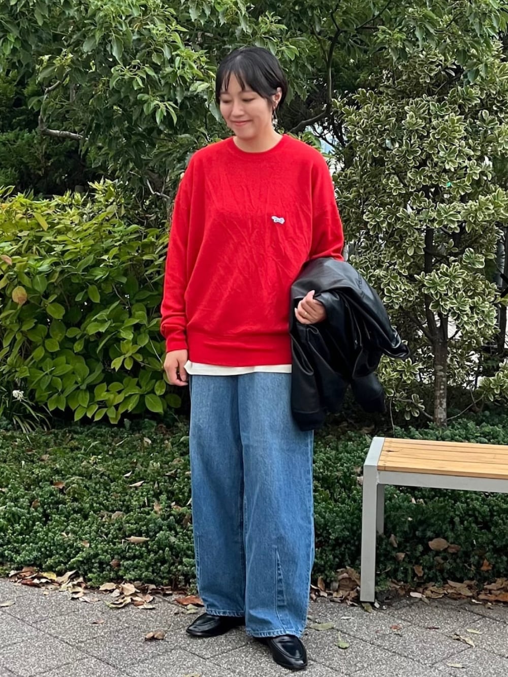 ブラック系のブルゾン、レッド系のニット/セーター、ブルー系のデニムパンツを着用したレディースの秋コーディネートの2枚目の写真