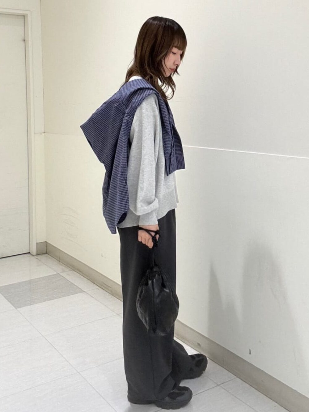ブラック系のショルダーバッグ、グレー系のニット/セーター、ブルー系のシャツ/ブラウスを着用したレディースの秋コーディネートの2枚目の写真