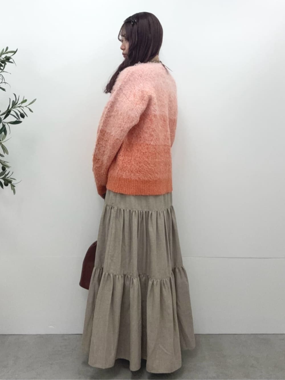 ブラウン系のショルダーバッグ、オレンジ系のニット/セーター、ベージュ系のスカートを着用したレディースの冬コーディネートの2枚目の写真