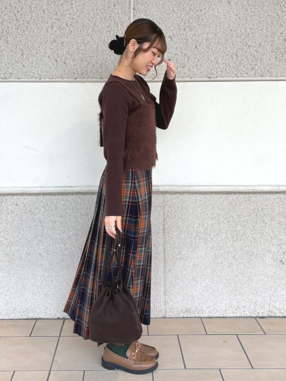 ブラウン系のニット/セーター、オレンジ系のスカートを着用したレディースの冬コーディネートの2枚目の写真