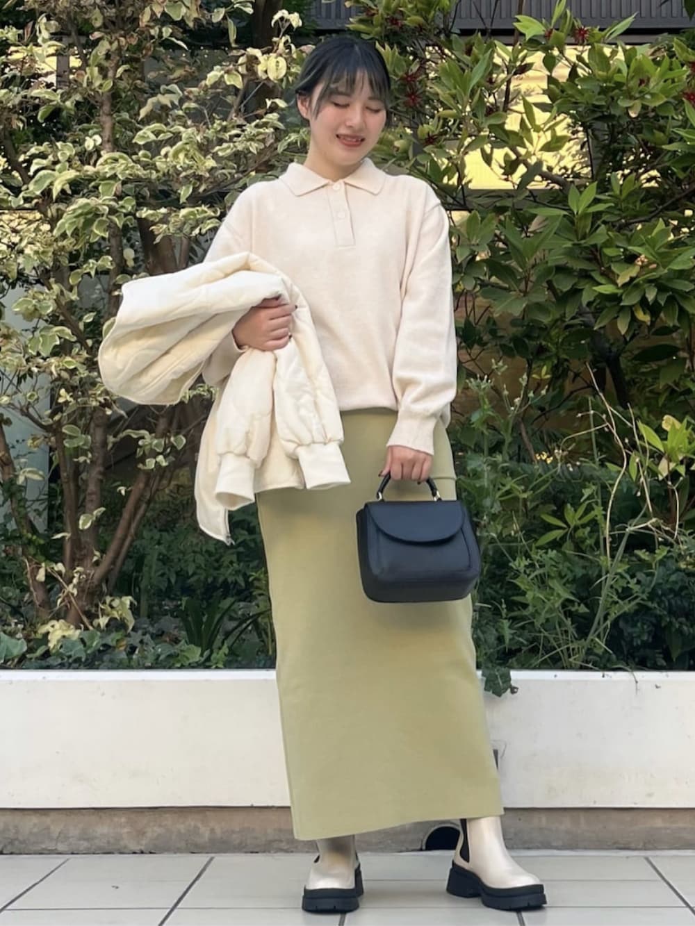 ホワイト系のノーカラージャケット、グリーン系のスカート、ホワイト系のニット/セーターを着用したレディースの秋コーディネートの2枚目の写真