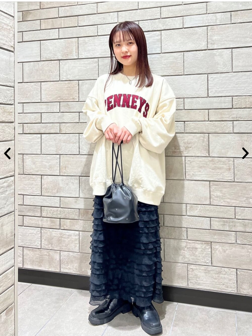 ベージュ系のスウェット、ブラック系のスカート、ブラック系のショルダーバッグを着用したレディースの秋コーディネートの2枚目の写真