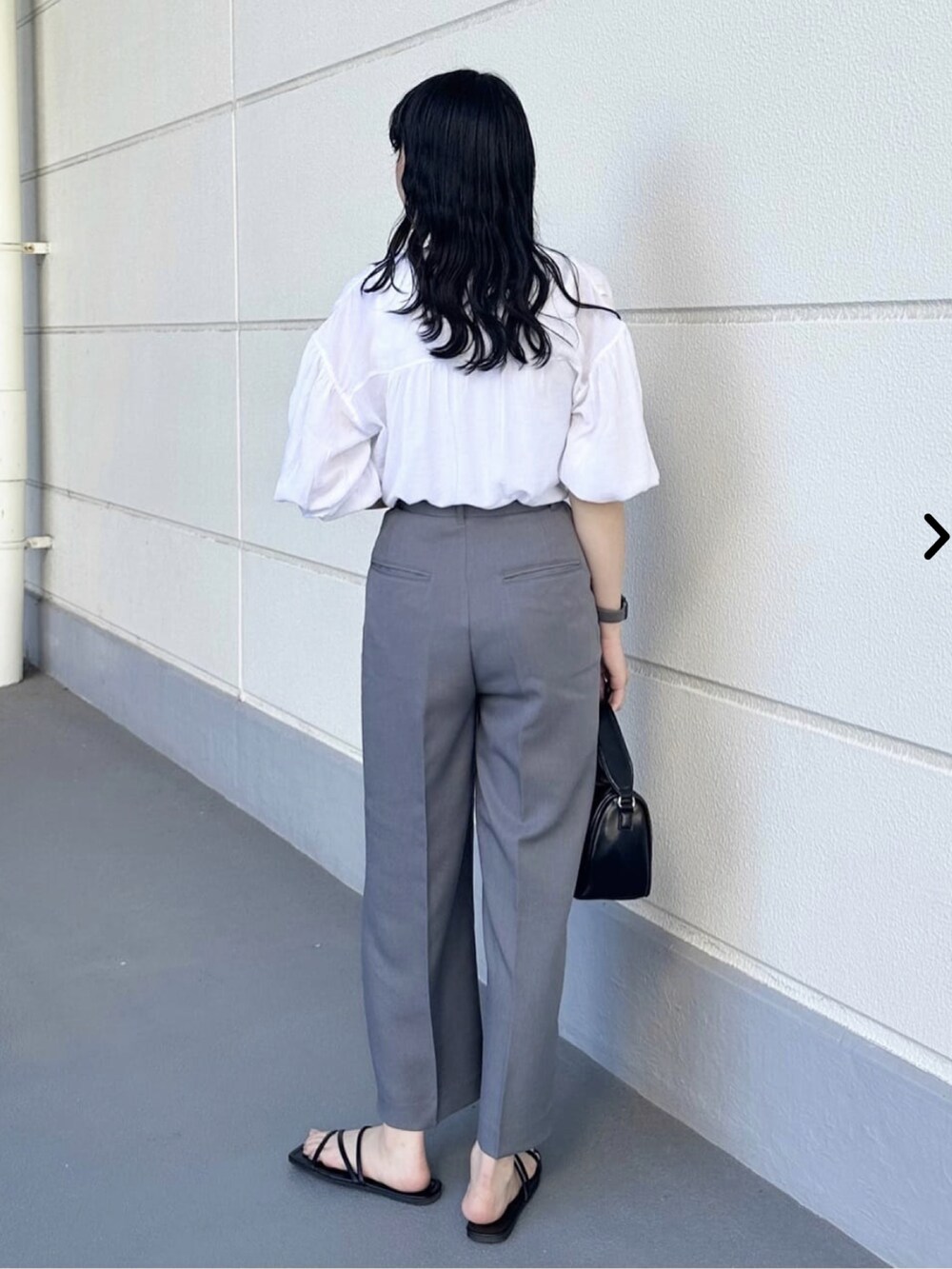 ホワイト系のシャツ/ブラウス、グレー系のスラックス、ブラック系のショルダーバッグを着用したレディースの夏コーディネートの3枚目の写真