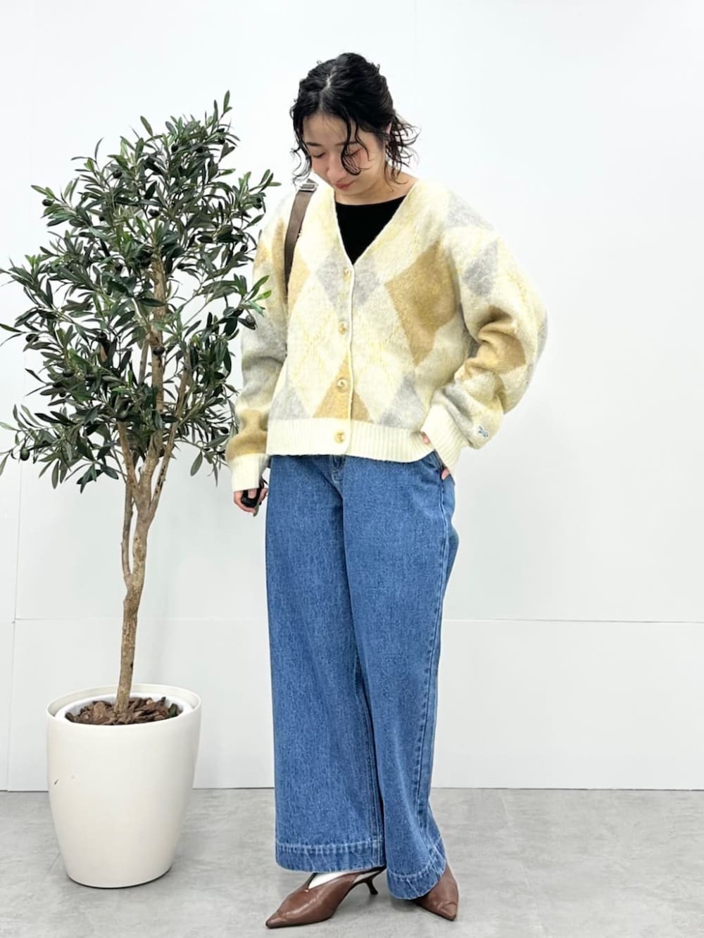 ベージュ系のカーディガン/ボレロ、ブルー系のデニムパンツ、ブラウン系のショルダーバッグを着用したレディースの秋コーディネートの2枚目の写真