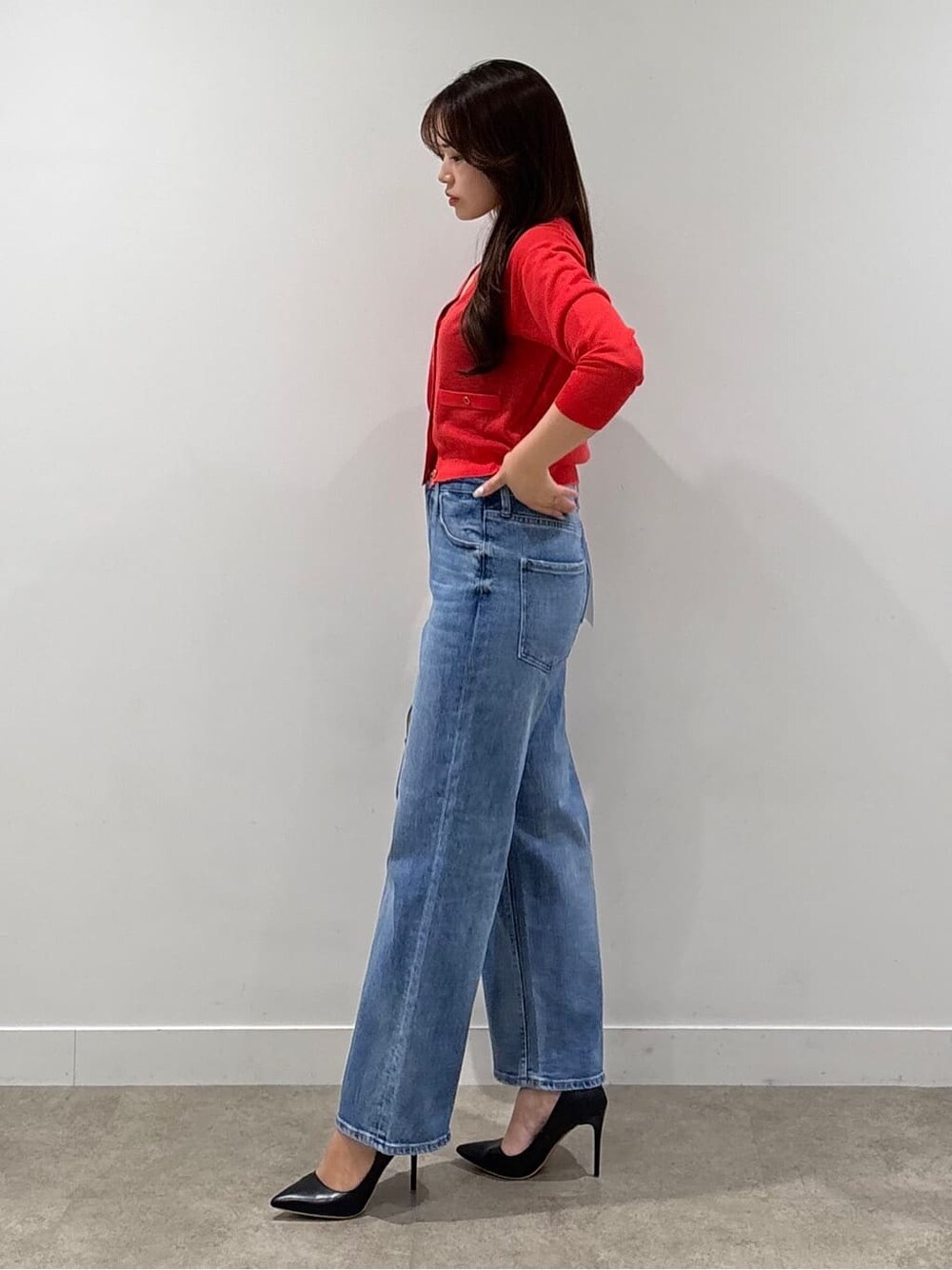 ブラック系のニット/セーター、レッド系のカーディガン/ボレロ、ブルー系のデニムパンツを着用したレディースの春コーディネートの2枚目の写真