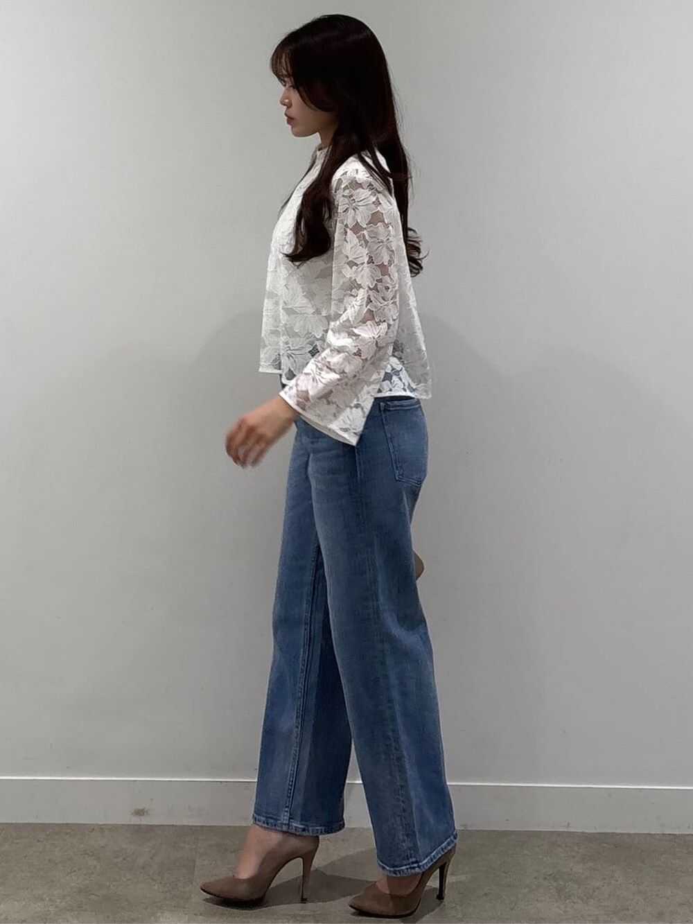 ホワイト系のシャツ/ブラウス、ホワイト系のニット/セーター、ブルー系のデニムパンツを着用したレディースの春コーディネートの2枚目の写真