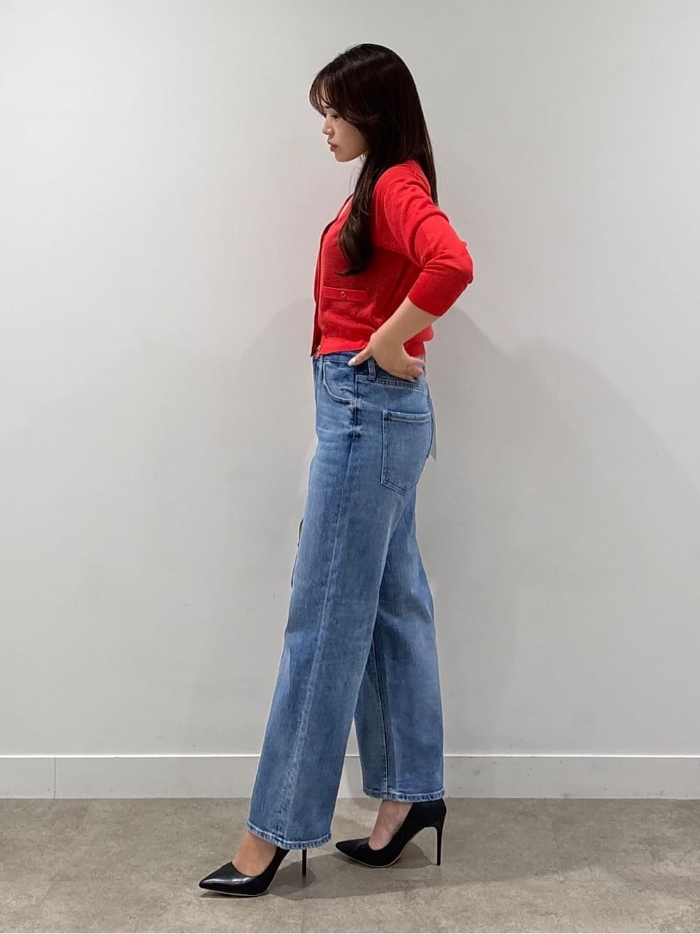 ブラック系のニット/セーター、レッド系のカーディガン/ボレロ、ブルー系のデニムパンツを着用したレディースの春コーディネートの2枚目の写真