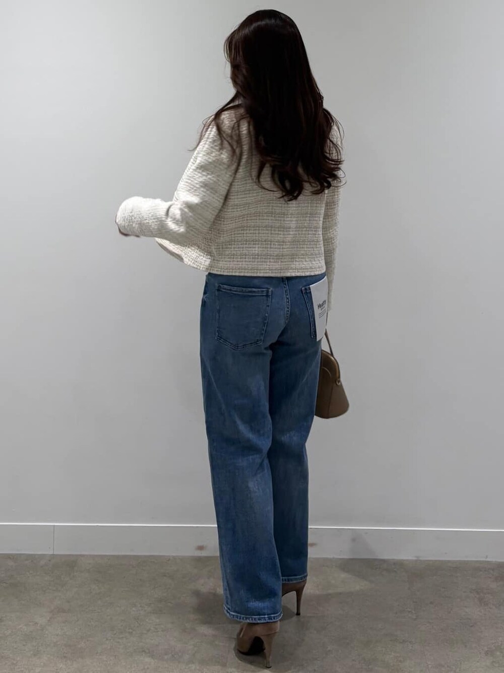 ベージュ系のノーカラージャケット、ホワイト系のニット/セーター、ブルー系のデニムパンツを着用したレディースの春コーディネートの3枚目の写真