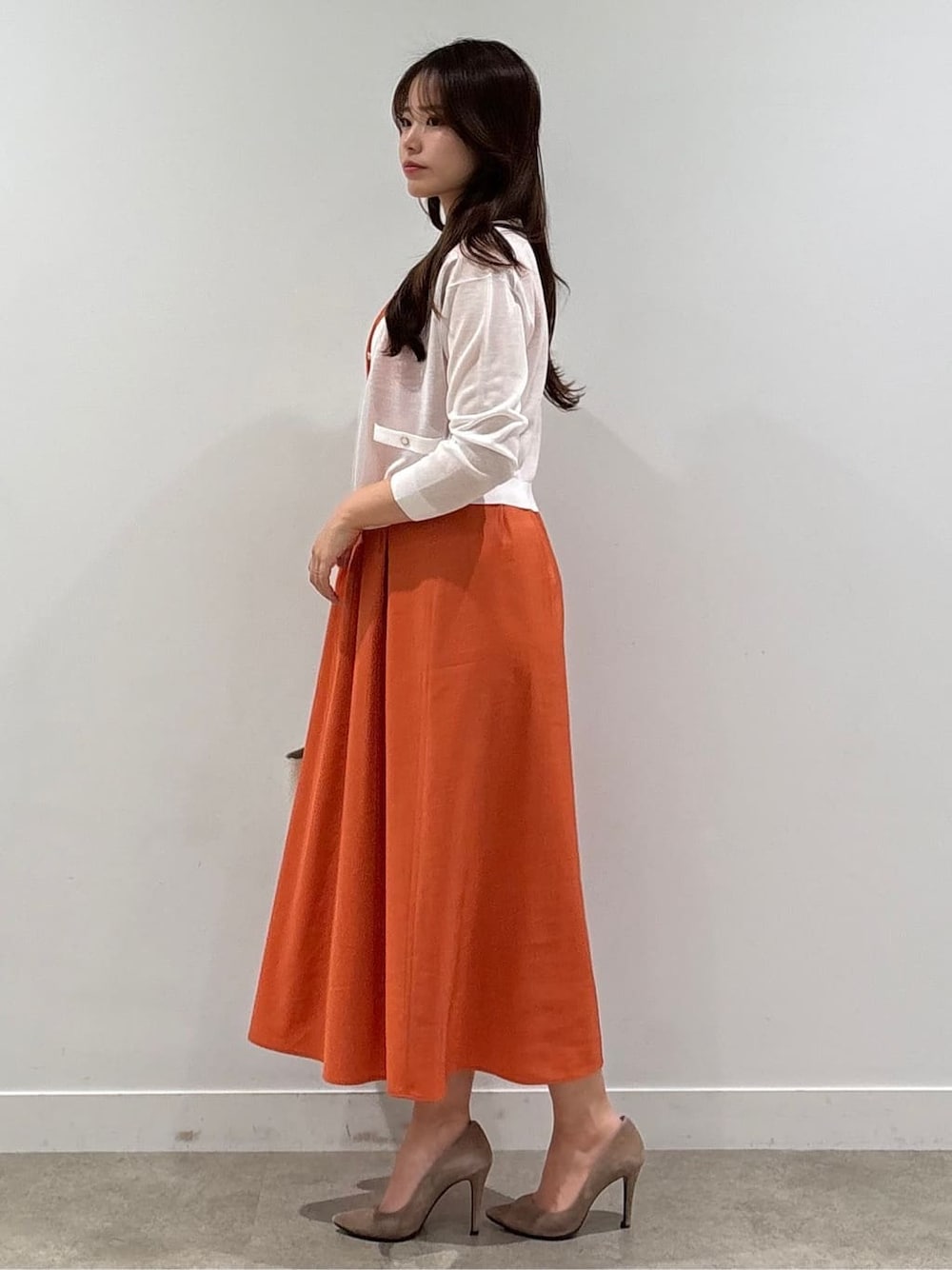 レッド系のワンピース、ホワイト系のカーディガン/ボレロを着用したレディースの春コーディネートの2枚目の写真