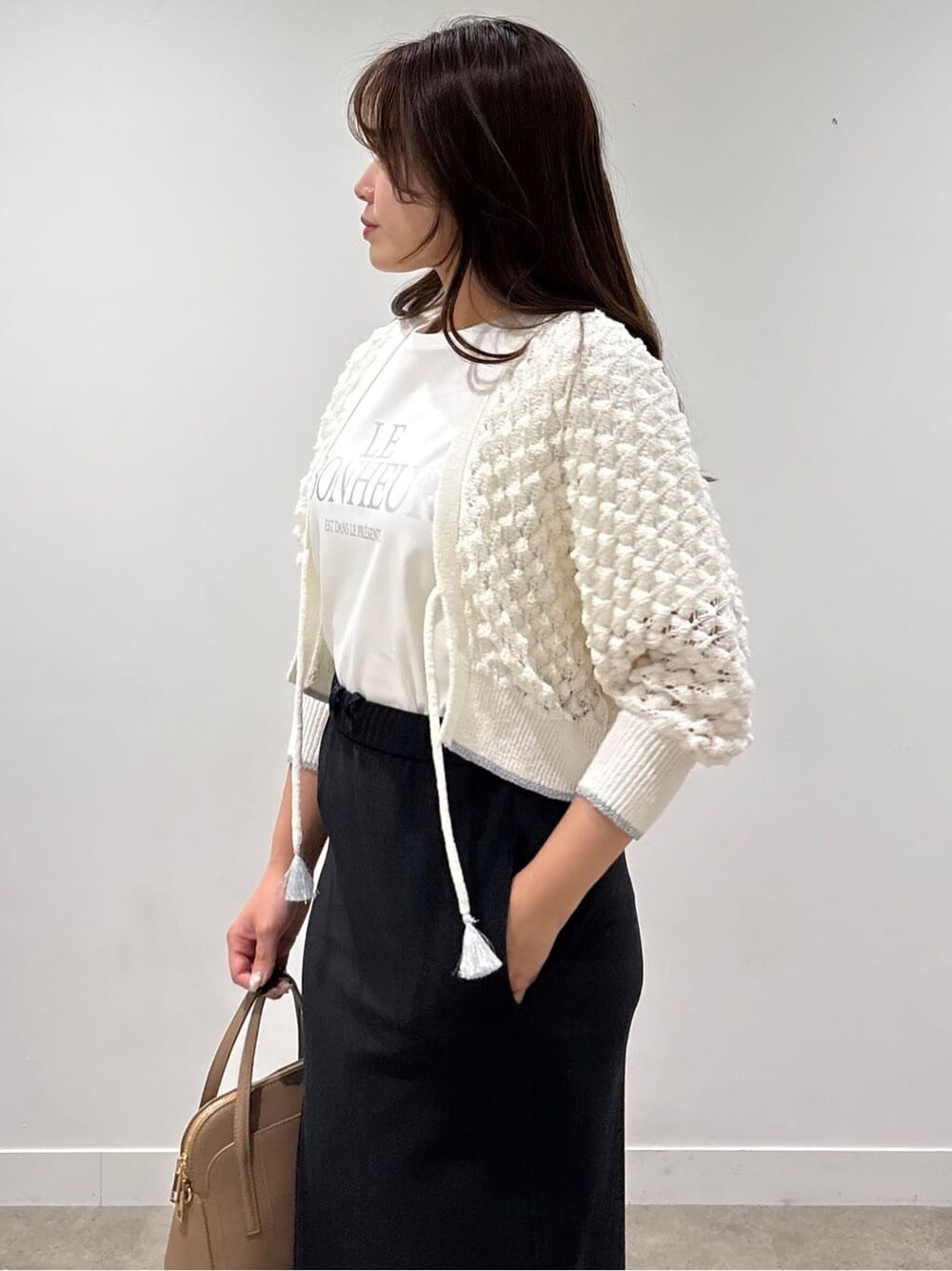 ホワイト系のカーディガン/ボレロ、ホワイト系のTシャツ/カットソー、ブラック系のスカートを着用したレディースの春コーディネートの5枚目の写真
