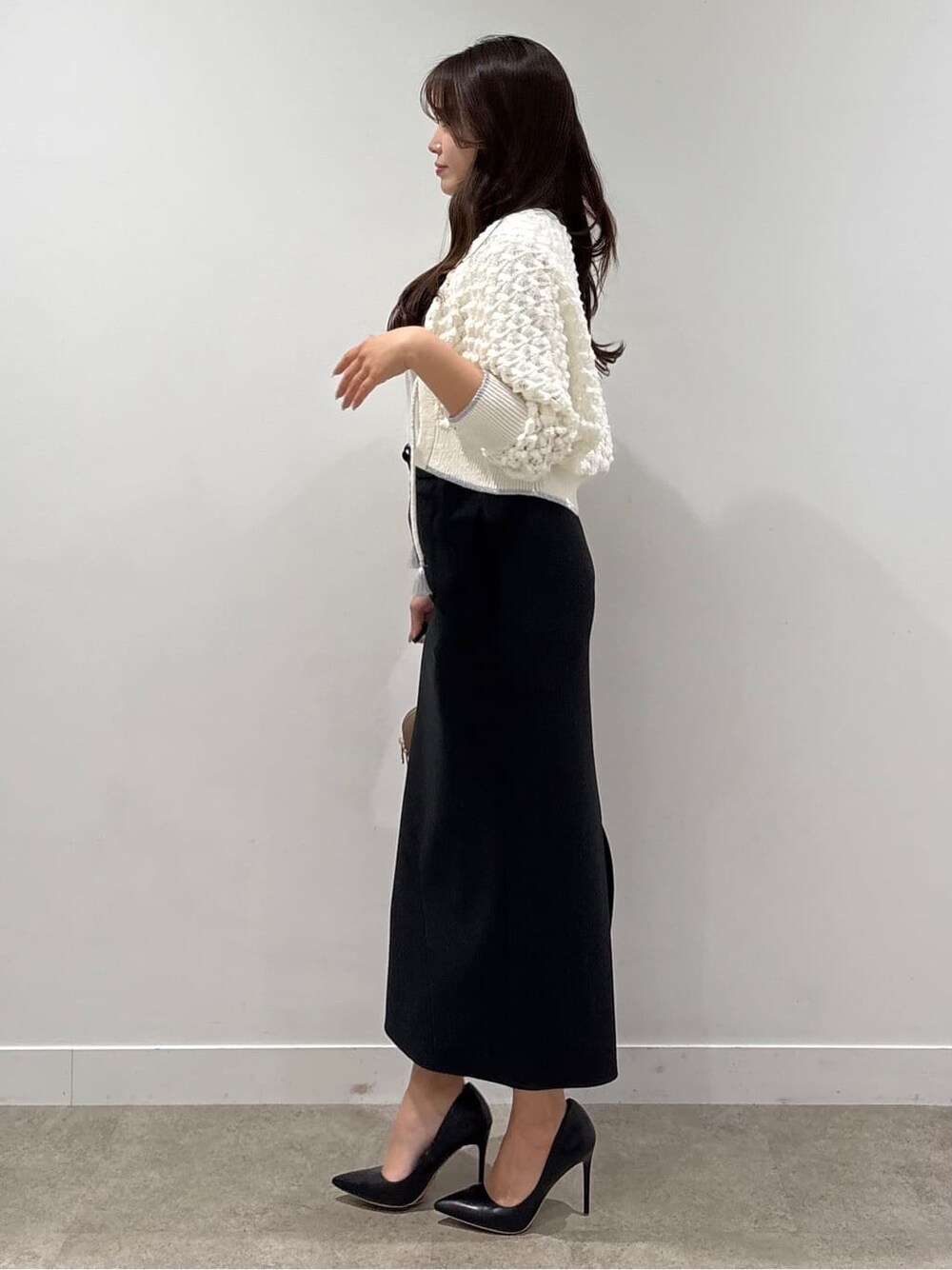 ホワイト系のカーディガン/ボレロ、ホワイト系のTシャツ/カットソー、ブラック系のスカートを着用したレディースの春コーディネートの2枚目の写真