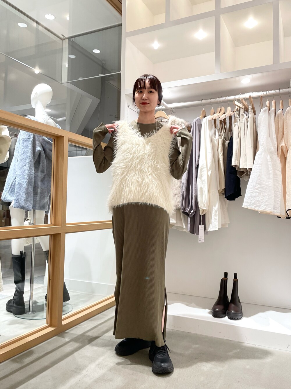 グリーン系のワンピース、ホワイト系のベストを着用したレディースの秋コーディネートの2枚目の写真