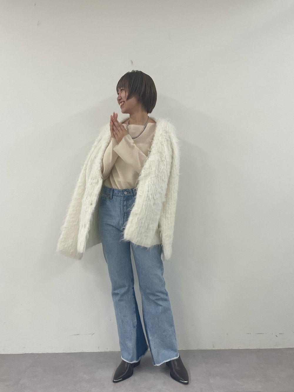 ホワイト系のカーディガン/ボレロ、ベージュ系のニット/セーター、ブルー系のデニムパンツを着用したレディースの秋コーディネートの2枚目の写真